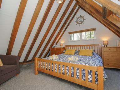 A bedroom with a wooden bed and beams on the ceiling at Stow Cottage in Davidstow near Camelford