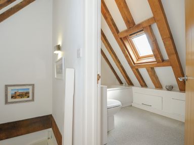 A bathroom with a toilet bathtub and skylight under a wooden beam ceiling at Stow Cottage in Davidstow near Camelford