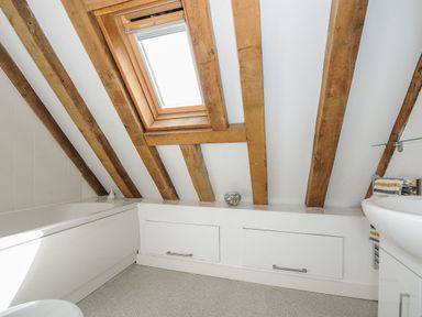 A bathroom with exposed wooden beams skylight bathtub and sink at Stow Cottage in Davidstow near Camelford
