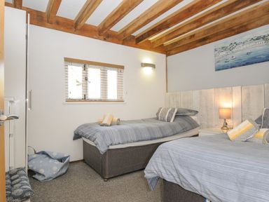 A bedroom with two single beds bedside table with lamp and window with blinds at Stow Cottage in Davidstow near Camelford