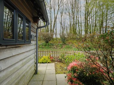 A small garden area with a wooden fence and shrubs next to a wooden building at Stow Cottage in Davidstow near Camelford