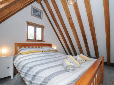 A bedroom with a wooden bed and beams on the ceiling at Stow Cottage in Davidstow near Camelford