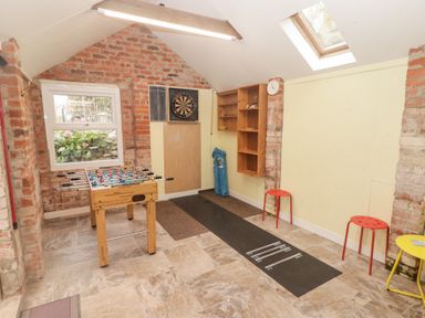 A game room with a foosball table dartboard shelving and two red stools at Morawel Newport Pembrokeshire