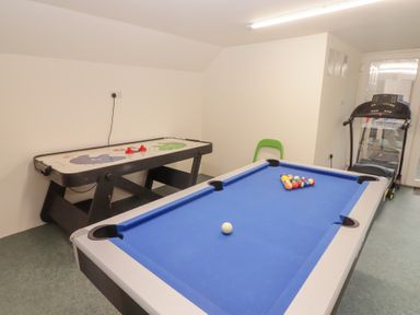 A recreation room with a blue pool table air hockey table and a treadmill at Morawel Newport Pembrokeshire