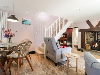 A dining area with glass table and chairs next to a living room with armchairs and a fireplace at Morawel Fach in Newport Pembrokeshire
