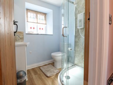 A bathroom with a shower cabin toilet sink window with stained glass at Morawel Fach in Newport Pembrokeshire