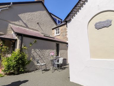 An outdoor seating area with two chairs and a small table with flowers outside a building at Morawel Fach in Newport Pembrokeshire