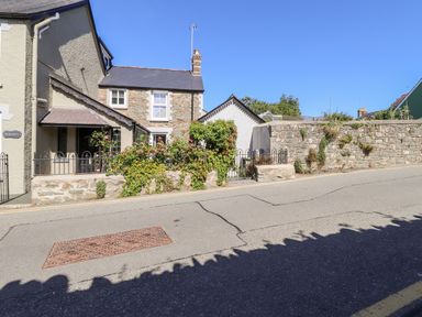 A street view of a stone house with a garden and a stone wall at Morawel Fach in Newport Pembrokeshire