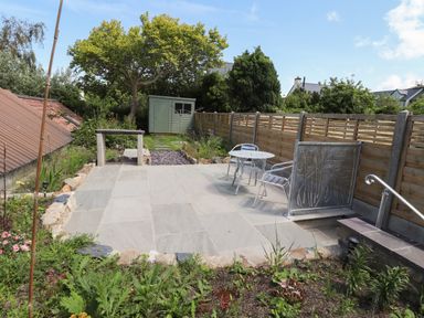 A garden patio with table and chairs next to a wooden fence and green shed in the background at Morawel Fach in Newport Pembrokeshire