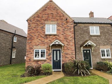 Two attached brick houses with black doors and white framed windows with small gardens and pathways in front