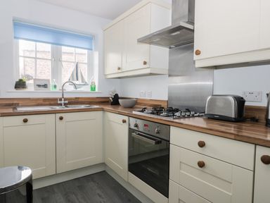 A kitchen with cream cabinets wooden countertops a gas stove an oven a double sink and a window at Silversands in Filey