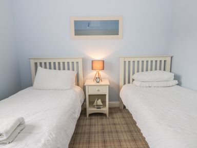 A bedroom with two single beds and a nightstand with a lamp and clock at Silversands in Filey