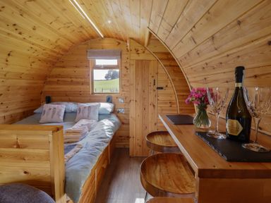 A sleeping area with bed and table at Embden Pod at Banwy Glamping Llanfair Caereinion