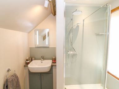 A bathroom with a sink and mirror next to a shower enclosure at Cherrywood Barn in South Petherton