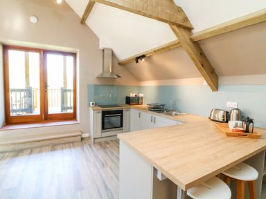 A kitchen with wooden beams wooden countertops and bar stools at Cherrywood Barn in South Petherton