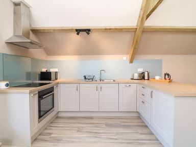 A kitchen with white cabinets a wooden countertop a stove an oven a microwave sink and small appliances at Cherrywood Barn in South Petherton