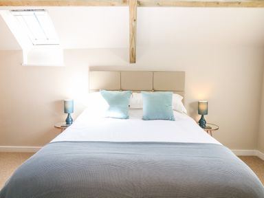 A bedroom with a bed blue pillows and lamps on side tables at Cherrywood Barn in South Petherton