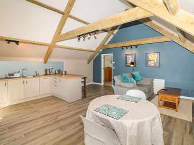An open plan kitchen and living area with wooden beams on the ceiling at Cherrywood Barn in South Petherton