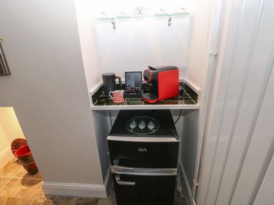 A small kitchenette area with a black mini fridge and a countertop holding a red coffee machine and a black electric kettle at Ty Coch y Castell in Pembroke