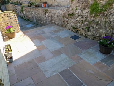 A stone patio with flower pots and a stone wall at Ty Coch y Castell in Pembroke