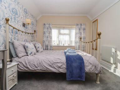 A bedroom with a metal bed frame bedding and folded towels on the bed beside a window with curtains at Mollys Bit Church Westcote near Bourton-On-The-Water