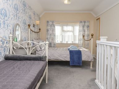 A bedroom with two beds a vanity table with a mirror and window with curtains at Molly's Bit in Church Westcote near Bourton-On-The-Water
