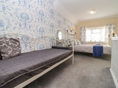 A bedroom with two beds a vanity table and a window with curtains at Molly's Bit Church Westcote near Bourton-On-The-Water