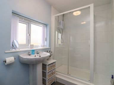 A bathroom with a sink storage drawers and a shower cubicle at Mollys Bit Church Westcote near Bourton-On-The-Water