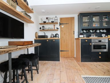 A kitchen with black cabinets wooden countertops wooden shelves and stools with black fur covers at Rocket Cart House in Lizard