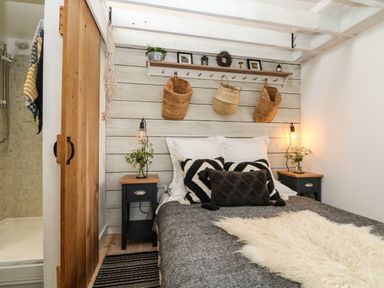 A bedroom with a bed flanked by two nightstands and a wooden sliding door leading to a shower at Rocket Cart House in Lizard
