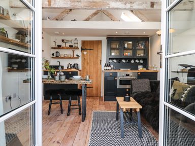 A kitchen and dining area with wooden floors black cabinets and a table with chairs at Rocket Cart House in Lizard