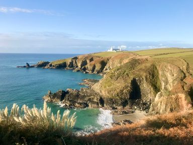 A coastal landscape with cliffs ocean and a building in the distance at Rocket Cart House in Lizard