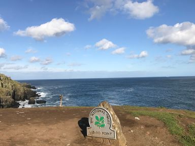 A coastal cliff with a national trust sign reading lizard point overlooking the ocean at Rocket Cart House in Lizard