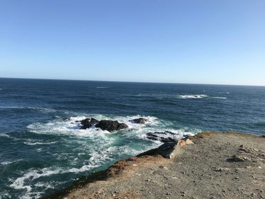 A cliffside view overlooking ocean waves crashing against rocks at Rocket Cart House in Lizard