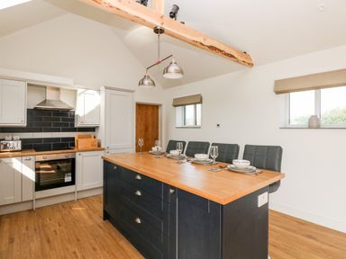 A kitchen with an island counter set with dishes and glasses next to cabinets and an oven at Glowty Brynbedw in Efailwen