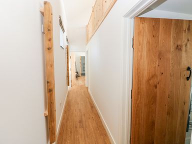 A hallway with wooden floor and wooden doors with white walls at Glowty Brynbedw in Efailwen