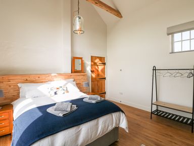 A bedroom with a bed towels hanging rack wooden door and window at Glowty Brynbedw in Efailwen