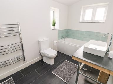 A bathroom with a toilet bathtub sink and towel rack at Glowty Brynbedw in Efailwen