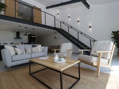 A living room with a sofa armchairs coffee table and staircase at Tilia Barn in Wincanton
