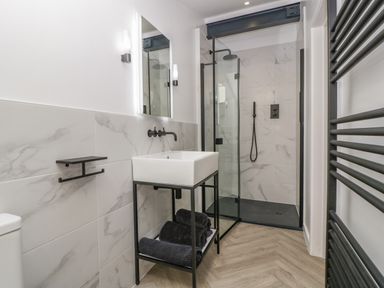 A bathroom with a sink and mirror next to a walk-in shower at Tilia Barn in Wincanton