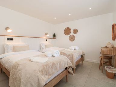 A bedroom with two single beds a wooden desk with chair and wall decor at Tilia Barn in Wincanton