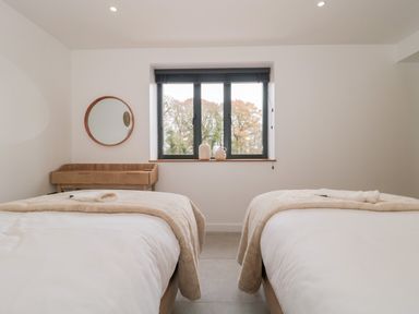 A bedroom with two beds a window and a wooden desk at Tilia Barn in Wincanton