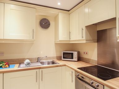A kitchen with cream cabinets a sink a microwave and an electric stove at Nautical Breeze in Weymouth
