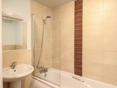 A bathroom with a bathtub shower combination and a sink at Nautical Breeze in Weymouth