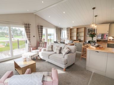An open living and kitchen area with sofas dining table and kitchen island at Sea Holly Lodge in Runswick Bay
