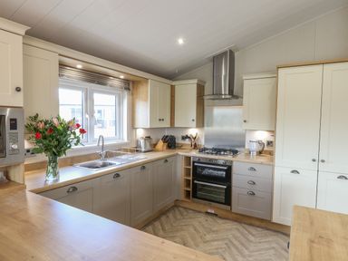 A kitchen with a vase of flowers on the counter a stove oven a sink and cabinets at Sea Holly Lodge in Runswick Bay