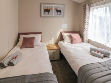 A bedroom with two single beds separated by a wooden nightstand at Sea Holly Lodge in Runswick Bay