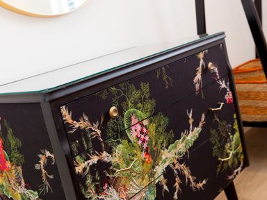 A close up of a black dresser with floral patterns and gold handles in a room at Sea Sands in Praa Sands