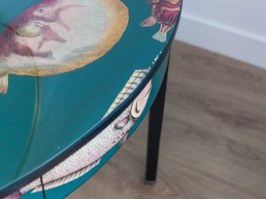 A round table with fish illustrations on a wooden floor at Sea Sands in Praa Sands