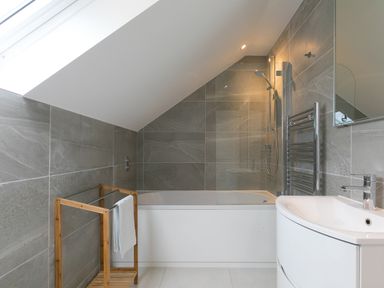 A bathroom with a bathtub shower combination towel rack and sink at Sea Sands in Praa Sands